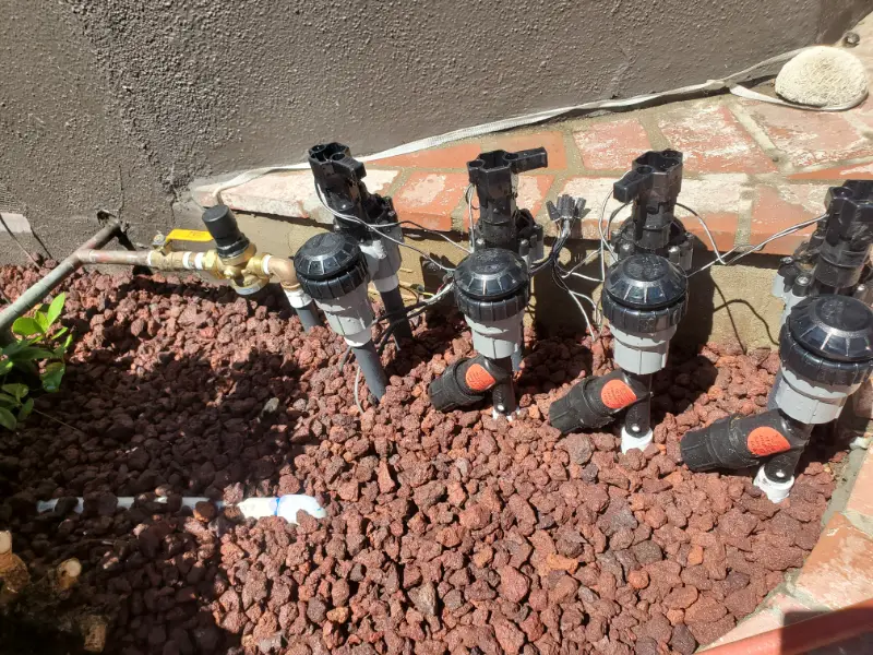 Close-up of drip irrigation risers installed over a gravel bed