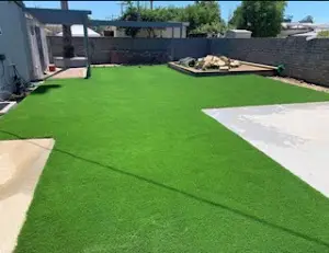 Backyard artificial turf lawn inset with a concrete paver walkway