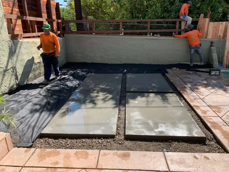 Crew laying the base for a block retaining wall and patio