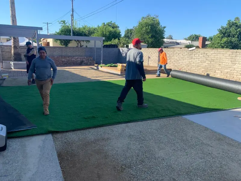 General Native Green crew rolling out and fitting artificial turf on a prepared base