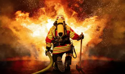 A firefighter in full protective equipment and respiratory gear working against flames
